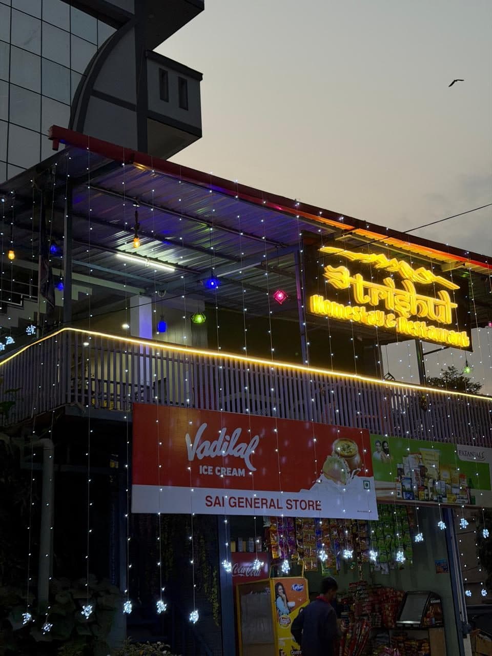 Rooftop terrace and signboard glowing with string lights at night