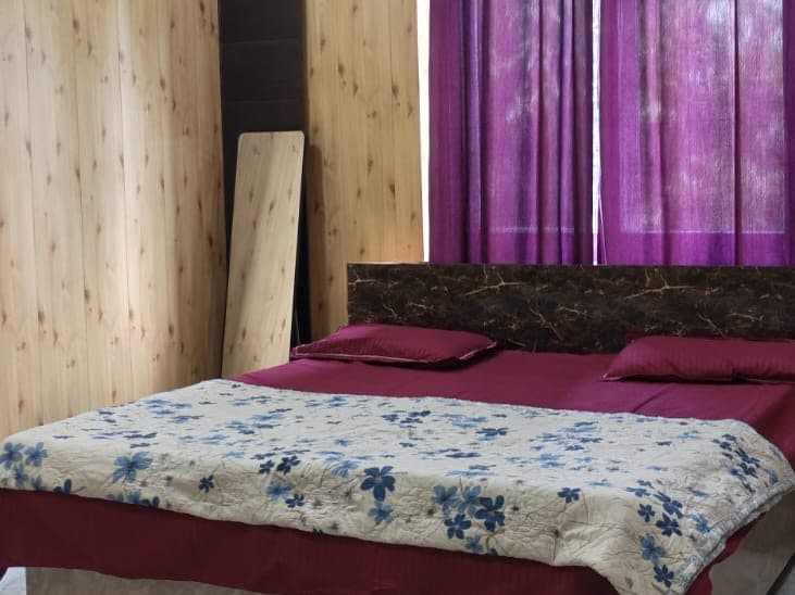 Guest room with a double bed, wood-panelled walls and purple curtains